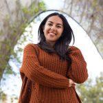 Cheerful mixed race girl in sweater walking in park
