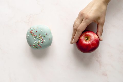person-choosing-apple-donut-against-white-background
